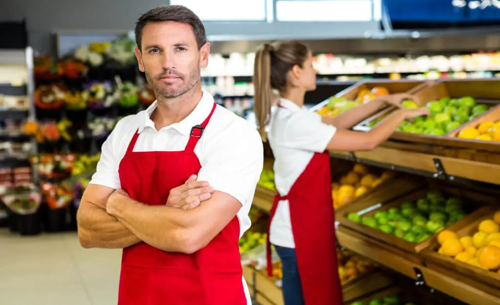 cost to start a grocery store - guy standing in grocery store
